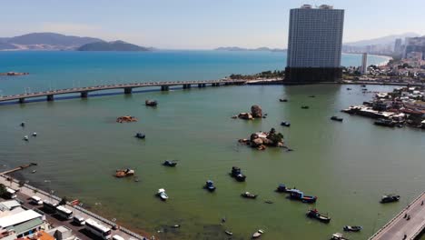 Drone-view-of-Nha-Trang-seaside-with-road-bridges-and-tall-city-buildings-in-background-during-sunny-day-in-Vietnam