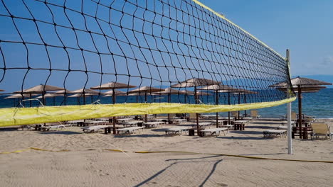 Wind-Weht-Beachvolleyballnetz-In-Der-Nähe-Der-Sonnenliegen-Und-Strohschirme