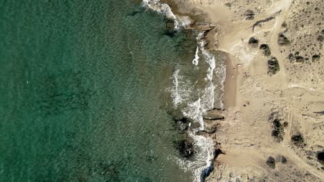 Still-shot-of-turquoise-blue-waves-rolling-onto-sandy-Mediterranean-coastline