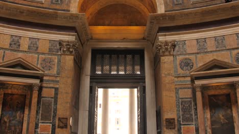 Beautiful-tilting-shot-of-famous-Pantheon-interior-entrance,-ceiling-and-facade-in-Rome,-Italy