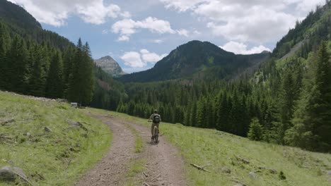 Toma-Aérea-De-Un-Ciclista-Con-Bicicleta-De-Montaña-Montando-En-El-Camino-Entre-Las-Montañas-Dolomitas-En-Verano---Hermoso-Panorama-Montañoso-En-Italia