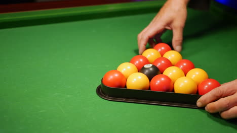 A-man-setting-up-the-pool-balls-on-a-table-in-a-triangle