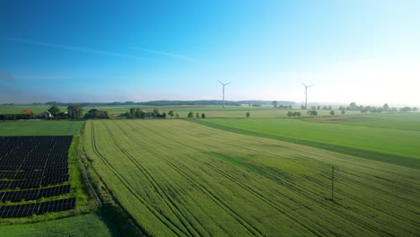 Aerial-panoramic-shot-showing-agricultural-fields-with-installed-solar-panel-farm-and-windmills-for-clean-green-energy