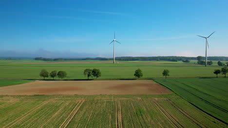 Aerial-trucking-shot-showing-cars-on-rural-road-and-spinning-wind-turbines-on-field-in-background---Beautiful-sunny-day-with-blue-sky-in-nature