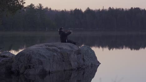 Native-Woman-Plays-Flute-On-A-Lake-Rock-In-Algonquin-Park-At-Sunrise