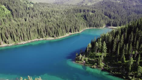 Cinematic-drone-aerial-over-a-beautiful-alpine-mountain-lake-surrounded-by-trees