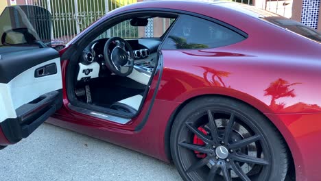 Gimbal-shot-view-of-expensive-supercar-Mercedez-AMG-GTS,-600hp-dark-red-car-with-the-door-open-with-while-black-leather-interior,-luxury-lifestyle