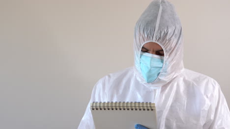 Doctor-in-PPE-suit-writing-in-a-notebook