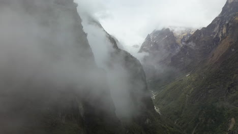 Epic-aerial-drone-shot-going-through-the-clouds-to-reveal-foggy-side-of-the-Annapurna-mountains,-Nepal