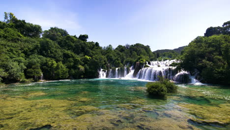 Tilt-up-from-colorful-water-to-wide-waterfalls-and-forest-at-Krka