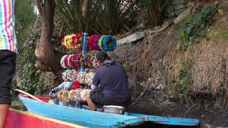 Blick-Auf-Einen-Verkäufer-Mit-Farbenfrohen-Blumenkopfbedeckungen-Auf-Einem-Boot,-Um-Ihn-Entlang-Der-Xochimilco-Kanäle-An-Touristen-Zu-Verkaufen