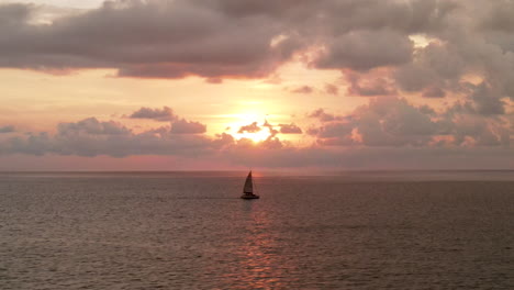 Static-shot-sailing-boat-passing-on-the-sea-during-epic-cloudy-sunset