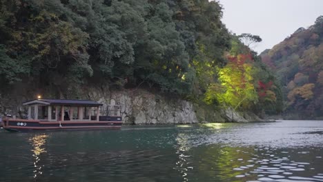 Boat-travels-up-Katsura-River-at-Arashiyama-in-late-fall-in-Japan