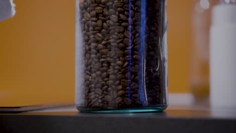 Schöne-Braune-Kaffeebohnen-In-Einem-Glasgefäß-Mit-Gelbem-Hintergrund