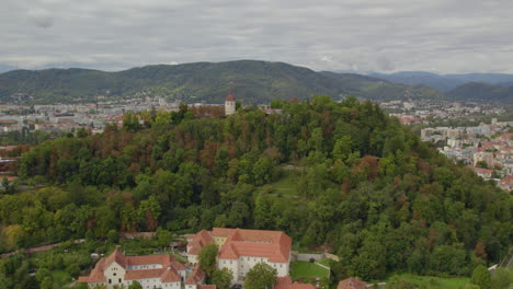 Aerial-view-heading-towards-Graz's-Schloßberg-dolomite-inner-city-hilltop-woodland-in-Graz-Austria