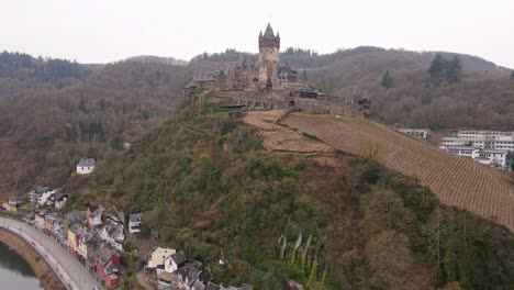 drone-footage-flying-to-cochem-castle-on-the-mountain-covered-with-vineyards-next-to-the-moselle-river-in-germany