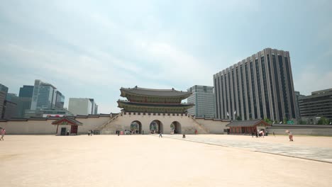 Kleine-Gruppen-Von-Besuchern-Gehen-Auf-Dem-Gyeongbokgung-Palastplatz-Mit-Dem-Gwanghwamun-Tor-Und-Dem-Seouler-Regierungsgebäude-Im-Hintergrund