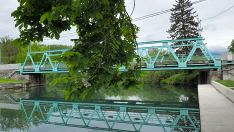 Turquoise-iron-bridge-with-walking-shot-and-tree-in-foreground