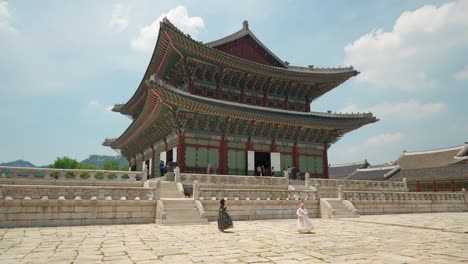 Girls-in-hanbok-clothes-take-photos-with-Gyeongbokgung-Palace-in-background-against-beautiful-sky