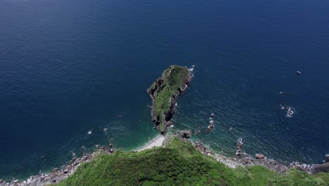 Aerial-view-straight-down-a-steep-cliff-towards-small-island-in-deep-blue-water-along-highway-9-in-East-Taiwan