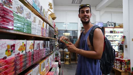 Male-Tourist-With-Backpack-Inside-Store-Picking-Up-Turkish-Delight-Box-From-Shelf