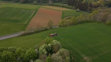 high-circular-drone-view-of-a-tractor-with-sprinkler-system-in-a-huge-green-meadow