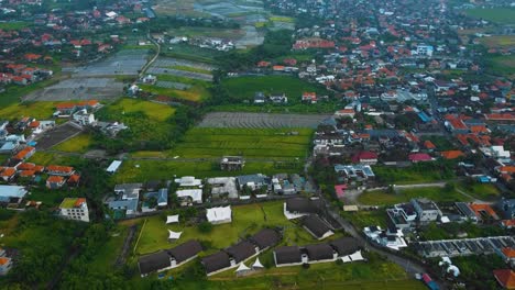 Cinematic-drone-footage-of-Berawa-beach-in-Canggu,-Bali-with-beautiful-landscape,-expensive-hotels,-rice-fields-and-villas-through-calm-weather