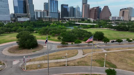 American-and-Texas-flags-wave-in-Austin,-Texas-breeze-in-front-of-the-city's-skyline