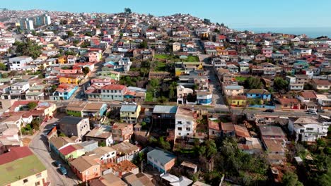 Aerial-dolly-in-of-colorful-neighborhood-houses-in-Playa-Ancha-Hill,-sea-in-background,-Valparaíso-city,-Chile
