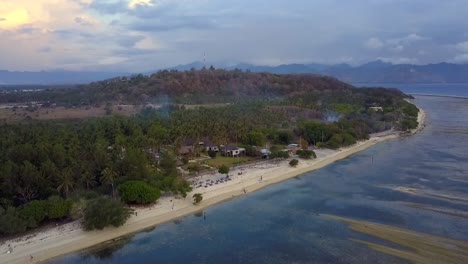 Chilling-on-the-beach-under-palm-trees-on-a-small-island-Smooth-aerial-view-flight-fly-forwards-sinking-down-drone-footage-of-Gili-T-at-sunset-summer-2017-Cinematic-view-from-above-by-Philipp-Marnitz