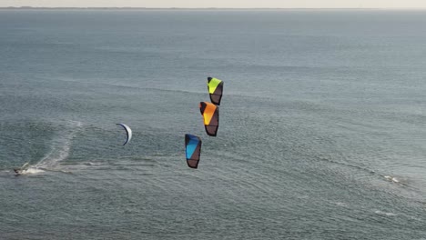 Three-multicolored-kites-hover-in-front-of-kitesurfer-riding-dutch-bay