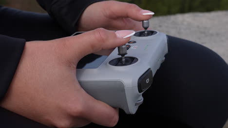 Weibliche-Hände-Und-Finger-Auf-Dem-Joystick-Der-DJI-Drohnenfernbedienung-Mit-Eingebautem-Bildschirm,-Nahaufnahme