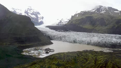 Glacier-in-Iceland-with-water-and-mountains-with-drone-video-moving-up-close-view