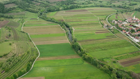 High-drone-shot-of-river-and-agriculture-fields,-roads,-vine-trees-and-small-village-on-the-side