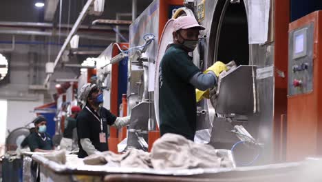 Männliche-Arbeiter-Entleeren-Große-Industrielle-Wäschetrockner-In-Einer-Fabrik-In-Pakistan