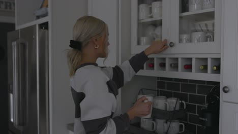 Woman-walking-up-to-a-cabinet-to-grab-a-cup-to-make-coffee