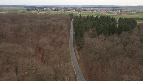 Aerial-approach-towards-an-empty-countryside-highway-with-one-oncoming-car-driving-out-of-frame