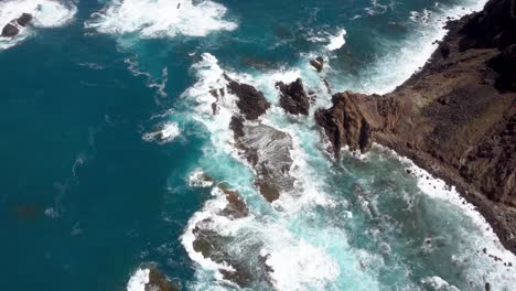 Waves-crashing-on-a-coast-with-rocks-blue-ocean-aerial-drone-bird-view