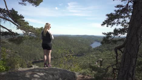 Gran-Paisaje-De-Las-Montañas-Del-Bosque-Noruego-Con-Una-Mujer-Excursionista-De-Pie-En-El-Mirador