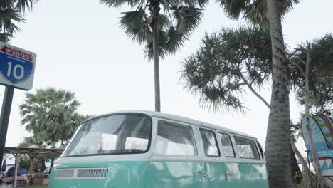 A-tilt-down-establishing-shot-of-an-iconic-Volkswagen-Van-parked-on-a-beach-in-Pattaya,-Chon-Buri,-Thailand