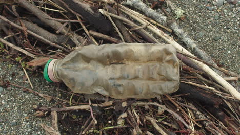 Nahaufnahme-Einer-Plastikflasche-Am-Strand,-Während-Die-Kamera-Von-Links-Nach-Rechts-Schwenkt