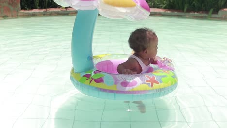A-shot-of-a-mixed-raced-baby-girl-in-a-flotation-device-in-a-swimming-pool