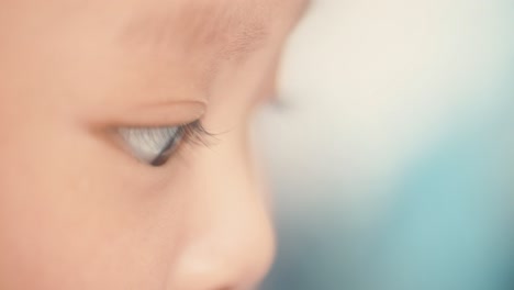 Close-up-of-young-Asian-baby's-face,-sat-up-playing-with-bokeh-background