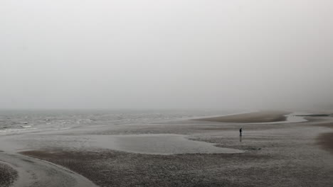 Hombre-Caminando-En-La-Playa-En-Un-Día-De-Niebla-En-Normandía