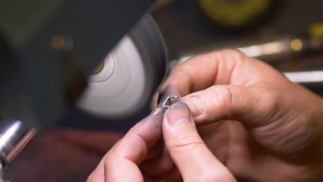 Hands-of-male-jewelry-maker-hand-polishing-and-buffing-a-silver-ring-in-a-jewellery-making-workshop