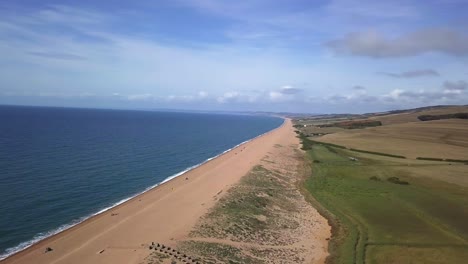 Aerial-tracking-from-right-to-left-with-slight-rotation-looking-up-the-vast-length-of-Chesil-Beach-looking-west,-from-the-fleet-lagoon