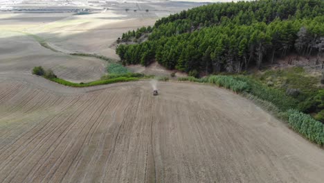 Schießen-Mit-Einer-Drohne-Auf-Einen-Traktor,-Der-Ein-Feld-In-Der-Landschaft-Apuliens-Bearbeitet