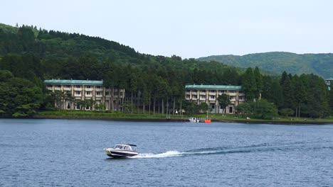 Der-Blick-Auf-Den-Ashi-See-Und-Einige-Gebäude,-Mit-Einem-Vorbeifahrenden-Motorboot