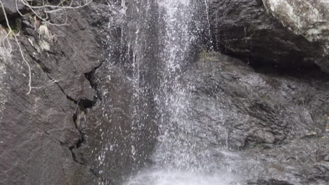 Water-falling-down-from-a-medium-waterfall-with-dark-brown-rocks