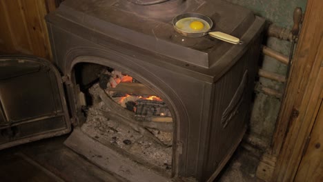 Opening-stove-and-filling-with-sticks-to-fry-an-egg